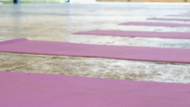 An empty concrete room with purple yoga mats laid out